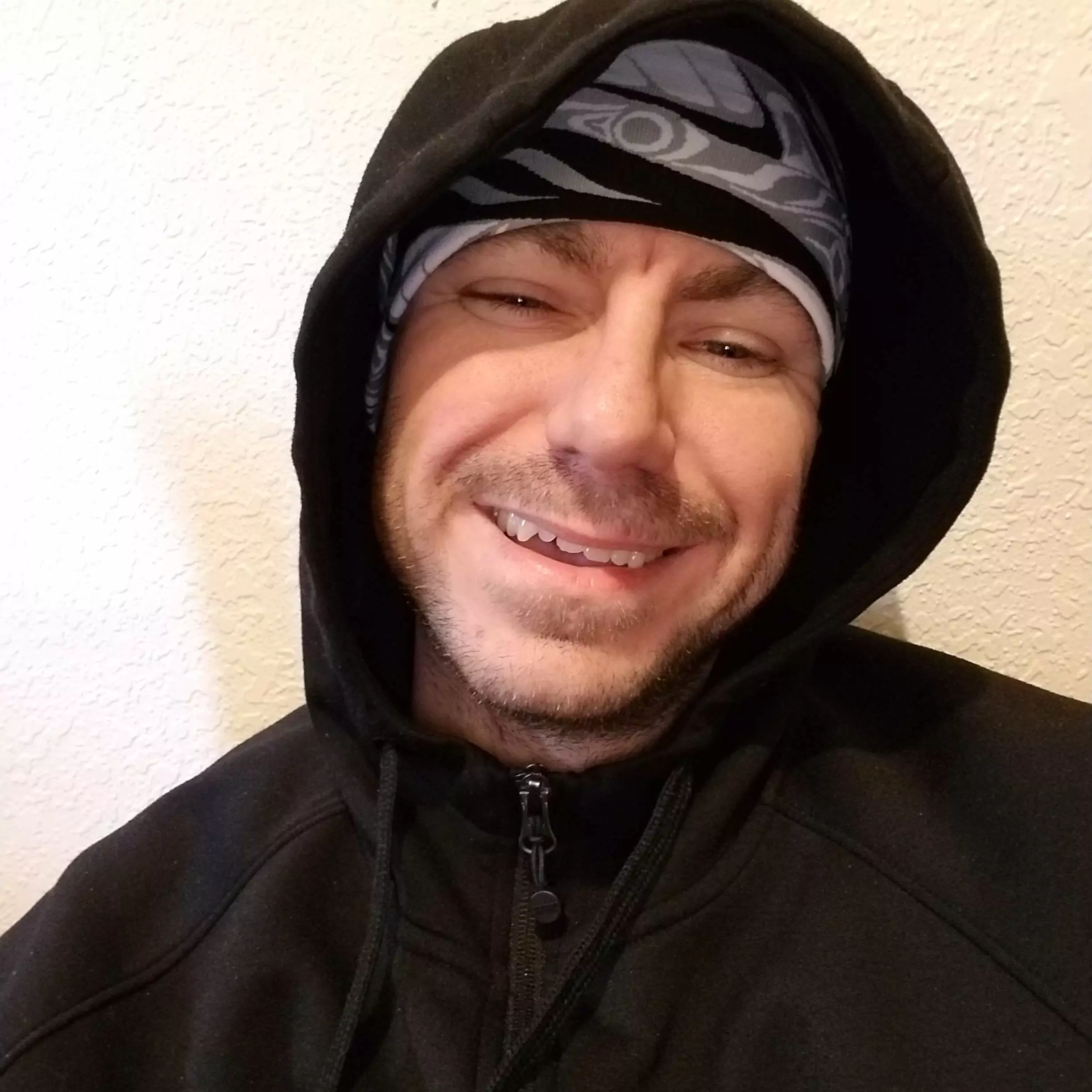 Chance Trahan inside his home in Juneau Alaska wearing a black hoodie and an alaskan Tlingit styled headband